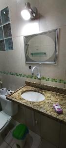 a bathroom with a sink and a toilet and a mirror at Casa do sossego - conforto, praia, piscina in Maricá +10 photos