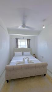 a large white bed in a room with a window at Alvy 2bedroom apartment in Mombasa
