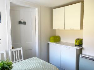 a kitchen with white cabinets and a green appliance at Kirnan Cottage in Kilmichael Glassary