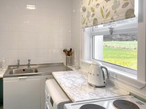 a white kitchen with a sink and a window at Kirnan Cottage in Kilmichael Glassary +16 photos