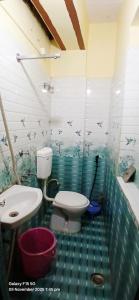 a green tiled bathroom with a toilet and a sink at Divya ganga hotel in Varanasi