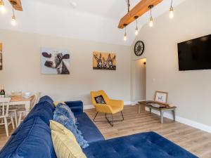 Una sala de estar con un sofá azul y un televisor en Dip Tub Den - Uk35989, en Wansford