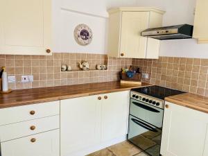 a kitchen with white cabinets and a stove top oven at The Parlour in Earls Croome