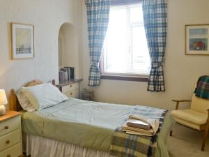 a bedroom with a bed and a chair and a window at Anchorage in Maidens