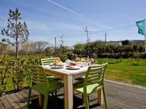 een houten tafel met groene stoelen en eten erop bij Una Argentum 60 in Carbis Bay