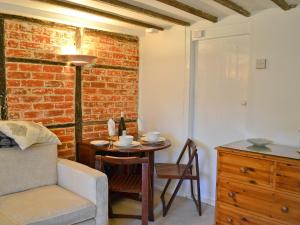 ein Wohnzimmer mit einem Tisch und einer Ziegelwand in der Unterkunft Rose Cottage in Hythe