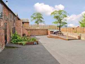 een binnenplaats met een bakstenen gebouw met een bank en bloemen bij The Old Stables in Helsby