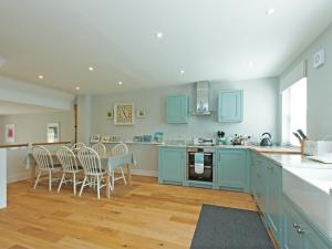 a kitchen with blue cabinets and a table and chairs at Eddystone Row 2 in Salcombe