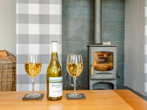 two glasses of white wine on a table with a fireplace at Sunnyside House in Duthil