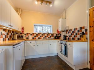 a kitchen with white cabinets and tiles on the wall at The Milking Shed - Uk30436 in Kingsbury Episcopi +6 photos