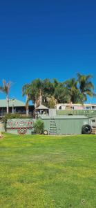 a park with green grass and palm trees and a building at One Life Live It Farm stay Retro VanStay in Dareton +33 photos