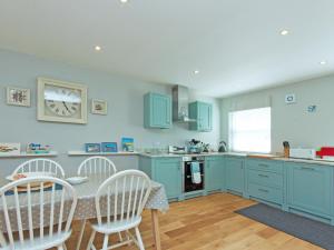 a kitchen with blue cabinets and a table and chairs at Eddystone Row 2 in Salcombe