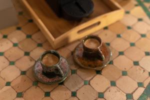Zwei Tassen stehen auf dem Badezimmerboden. in der Unterkunft Riad Privé Dar El Khamsa-Petit Dej inclus in Marrakesch