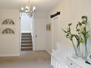 een hal met een trap en een vaas met bloemen bij Dray Cottage in East Allington