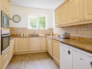 eine Küche mit Holzschränken und einer Uhr an der Wand in der Unterkunft On The Beach, East Yardley House - Uk31203 in Downderry