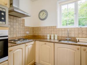 eine Küche mit Spüle und einer Uhr an der Wand in der Unterkunft On The Beach, East Yardley House - Uk31203 in Downderry + 28 Fotos