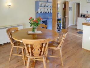 a wooden table with chairs and a vase with flowers on it at Bat's Cottage in Tipton Saint John