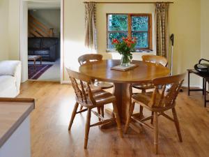 a dining room table with chairs and a vase of flowers at Bat's Cottage in Tipton Saint John