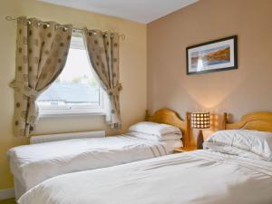 two beds in a room with a window at Serendipity in Keswick
