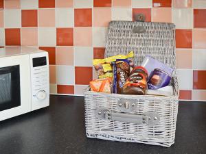 a basket filled with food next to a microwave at Lily Broad Cottage in Burgh Saint Margaret