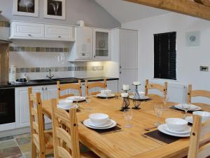 cocina con mesa de madera con sillas y comedor en The Top Barn, en Coedana