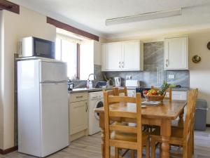 Saint EndellionにあるHaywain - Uk12084のテーブルと白い冷蔵庫のあるキッチン