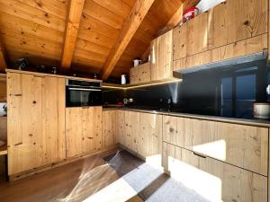 a kitchen with wooden cabinets and a black appliance at Appartamento Picchio in Bormio