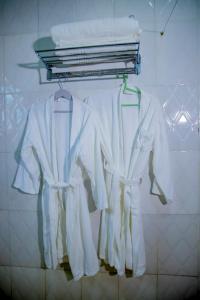 eine Gruppe weißer Hemden auf einem Kleiderständer in einem Badezimmer in der Unterkunft Kigufi Hill Hotel & Agape Resort in Gisenyi