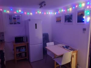 a kitchen with a white refrigerator and a table with chairs at Beechcroft 2 bed part house in Callington