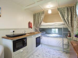 a kitchen with a sink and a bunk bed in a room at Honeysuckle Hut-Qu7066 in Melton Constable