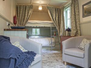 a living room with a bed and a couch and a chair at Honeysuckle Hut-Qu7066 in Melton Constable