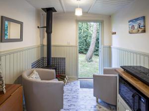 a living room with a fireplace and a stove at Honeysuckle Hut-Qu7066 in Melton Constable