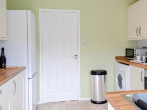 a white door in a kitchen with a trash can at Gwynt Y Môr in Tywyn
