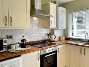 a kitchen with white cabinets and a sink at Gwynt Y Môr in Tywyn