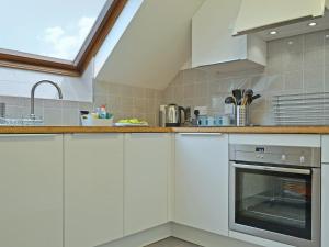 a kitchen with white cabinets and a sink at Herdwick Heights in Keswick
