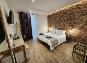 um quarto com uma cama grande e uma parede de tijolos em ARYA Cagliari em Cagliari