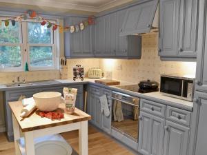 - une cuisine avec des placards bleus et une table avec un bol dans l'établissement Tower Cottage - Mvw, à Belsay