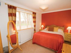 a bedroom with a bed with red walls and a window at Curlew Cottage - E3752 in Leverton