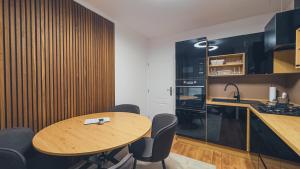 a kitchen with a wooden table and black cabinets at Apartmán Astana in Levoča