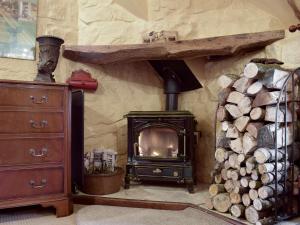 a wood stove in a room with a pile of logs at The Hayloft - Igp in Glaisdale