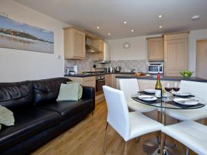 a living room and kitchen with a black leather couch at 1 Harbour View in Newquay