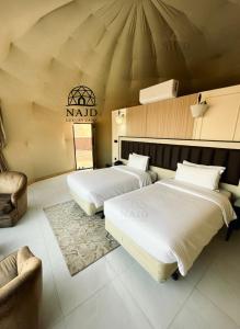 two beds in a room with a namd sign on the wall at Najd Luxury Camp in Wadi Rum +207 photos