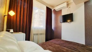 a bedroom with a bed and a television on the wall at Apple Hotel in Yerevan