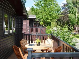 een houten terras met een tafel en stoelen bij Fern Lodge- Burnside Park in Keswick +2 foto's