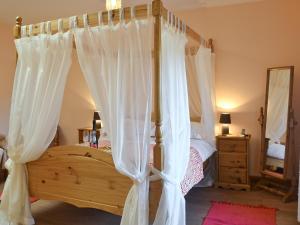 une chambre avec un lit à baldaquin avec des rideaux blancs dans l'établissement The Cottage - Osd, à Penbryn