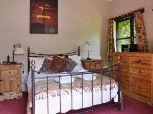 a bedroom with a bed and two dressers and a window at Brook Barn in Ellingham