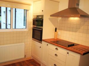 a kitchen with white cabinets and a stove top oven at Joan's Cottage in Braithwaite