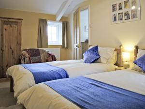 a bedroom with two beds with blue and white sheets at Cobweb Cottage in Whitby