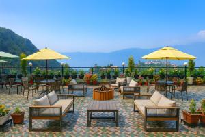 a patio with chairs and tables and yellow umbrellas at Doon Nature Valley Resort, Mussoorie in Mussoorie