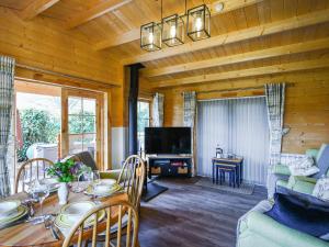 a living room with a table and a tv at Stable Lodge At Greenacre in Bromyard